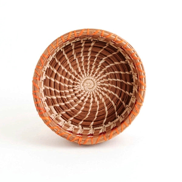 Woven basket with deep sides made from pine needles and colored raffia accents, available at Cerulean Arts. 