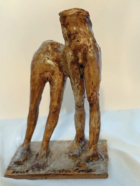 Ceramic sculpture of a standing figures on a white surface with a beige background