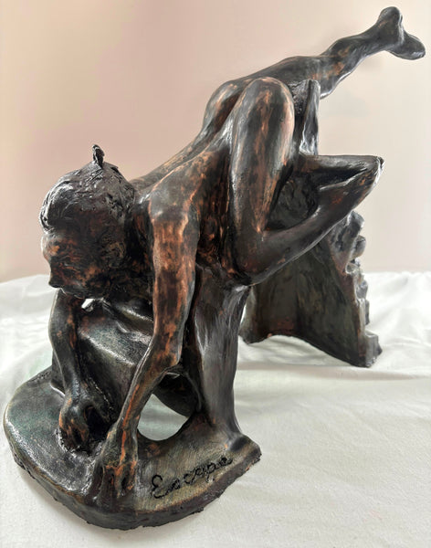 Ceramic sculpture of a falling human figure on a white surface with a beige background