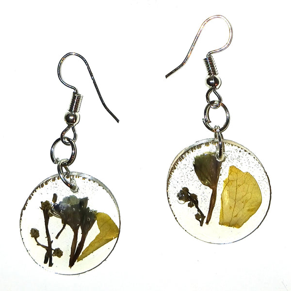 A pair of silver-tone dangle earrings with round clear resin pendants containing pressed dried botanical elements.