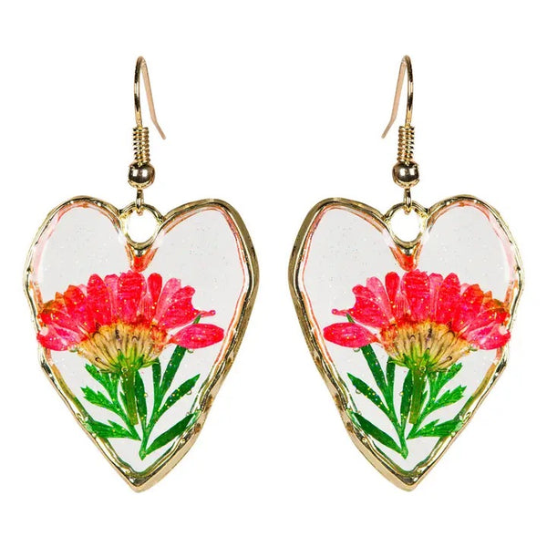 Heart shaped earrings with real dried flowers encased in resin with gold colored edging, available at Cerulean Arts.