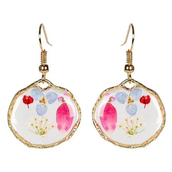 Round earrings with real dried flowers encased in resin with gold colored edging, available at Cerulean Arts.