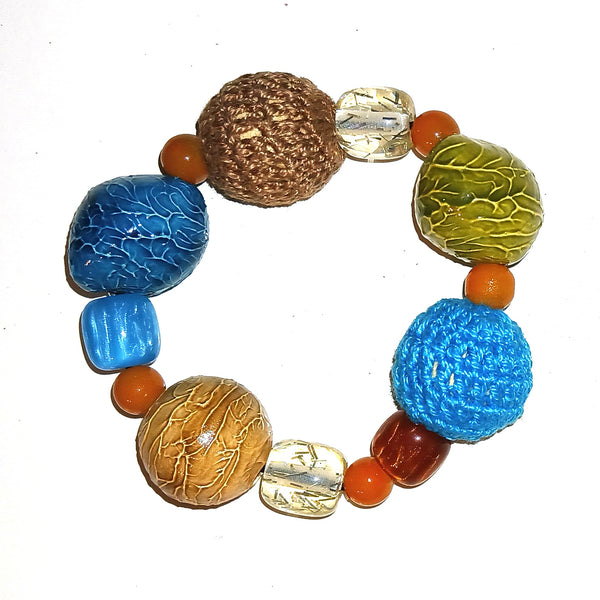 A handmade beaded bracelet featuring a variety of textured beads, including blue, brown, green, and orange, with clear patterned glass beads.