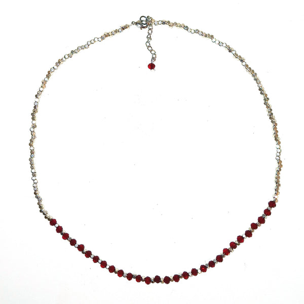 A silver-toned beaded necklace featuring a curved section of faceted dark red beads.