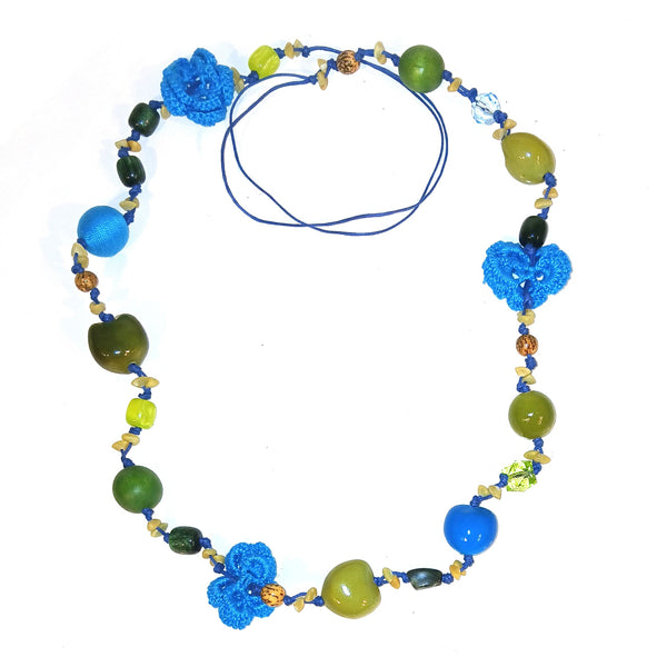 A beaded necklace with blue and green beads, three blue crochet flowers, and small gold-toned spacer beads with a blue cord.