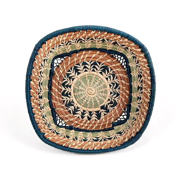 Woven basket with intricate pattern made from pine needles and colored raffia accents, available at Cerulean Arts.