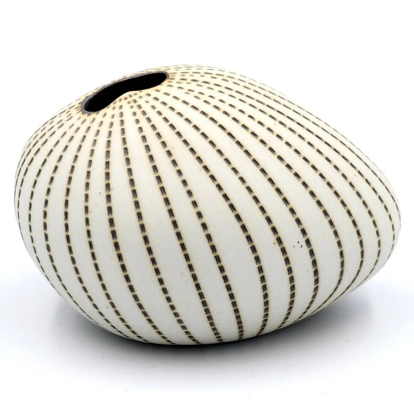 A small organic-shaped ceramic vase with a single opening at the top, decorated with vertical dashed lines in a warm brown or bronze tone on an off-white glazed base.