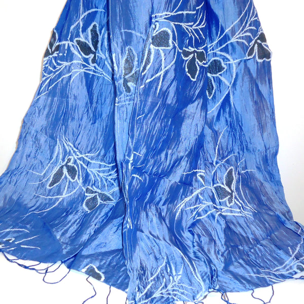 Silk scarf in iridescent blue printed with a gray and white floral motif, available at Cerulean Arts. 