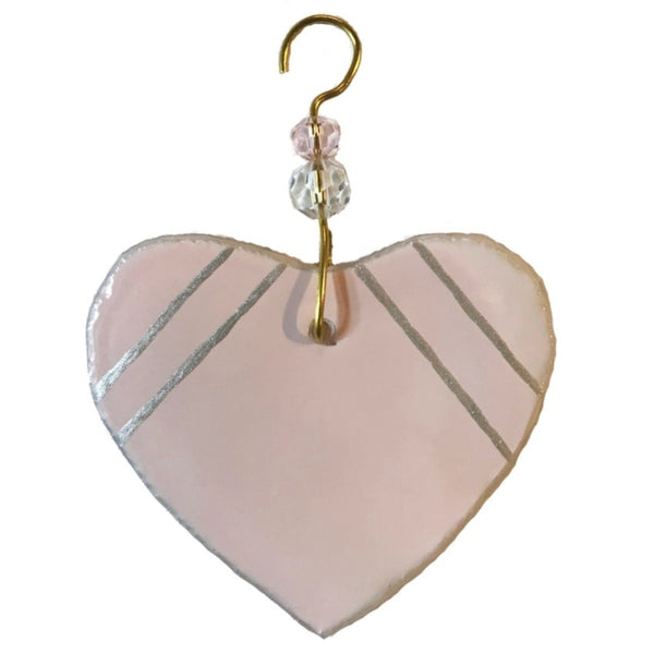 Fused glass suncatcher of a light pink heart with silver detailing made from recycled wine bottles, available at Cerulean Arts. 