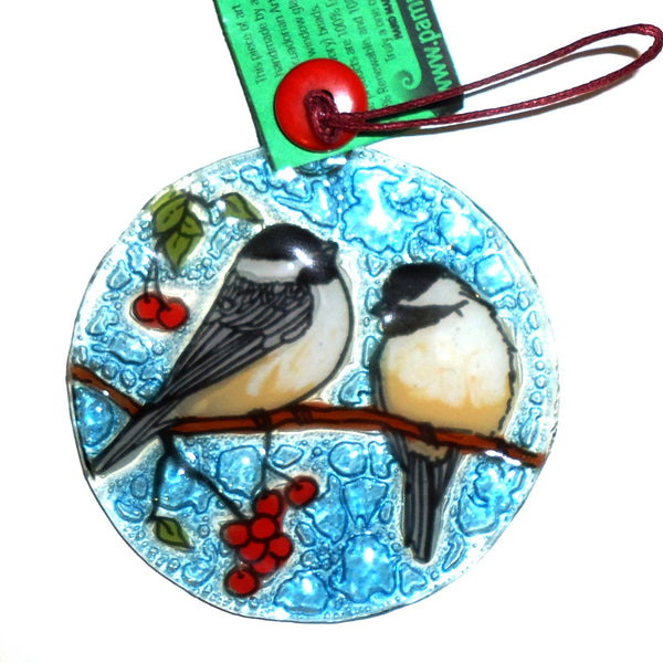 Fused glass suncatcher featuring a pair of chickadees sitting on a branch with berries, available at Cerulean Arts.