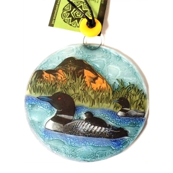 Fused glass suncatcher featuring a loon family swimming in a lake, available at Cerulean Arts.