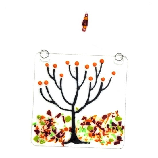 Fused glass suncatcher featuring a tree in autumn with colorful leaves below, available at Cerulean Arts.
