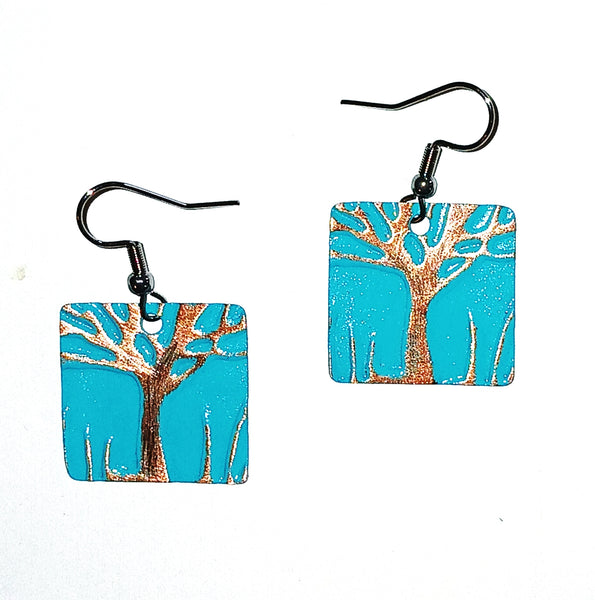 Square earrings with tree design on a teal background