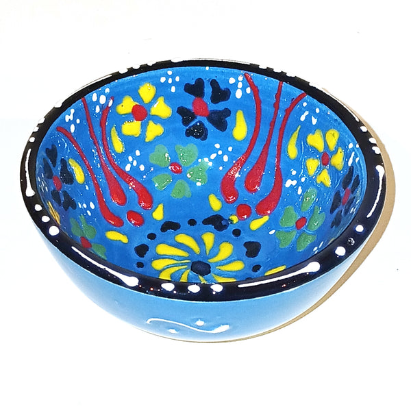 Decorative ceramic bowl with colorful floral patterns on a blue background