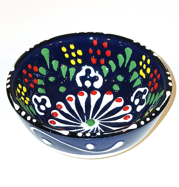 Decorative ceramic bowl with colorful patterns on a cobalt blue background
