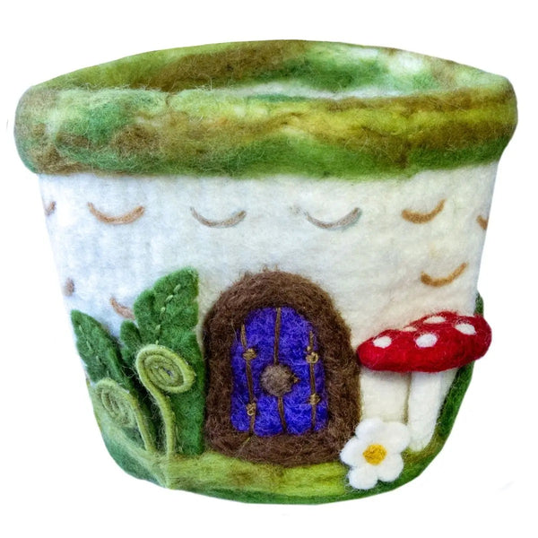 Felted woodland cottage pot with a purple door, red mushroom, and white flower on a green base.