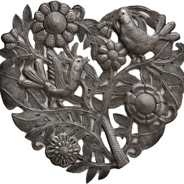 A heart-shaped silver metal wall art piece featuring carved birds perched among stylized flowers and leaves.