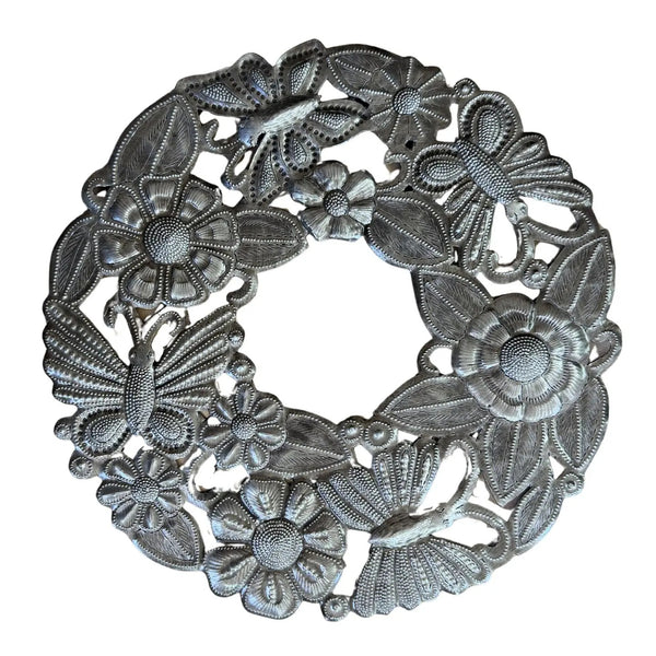 A circular silver-toned metal wall hanging featuring embossed floral and butterfly motifs.