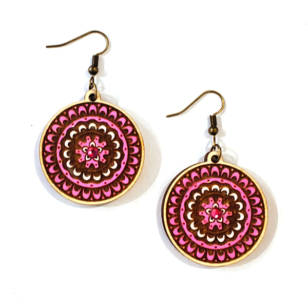 A pair of bohemian-style dangle earrings with circular mandala designs in vibrant pink, deep red, and white, with antique bronze fishhook wires, shown on a plain white background.