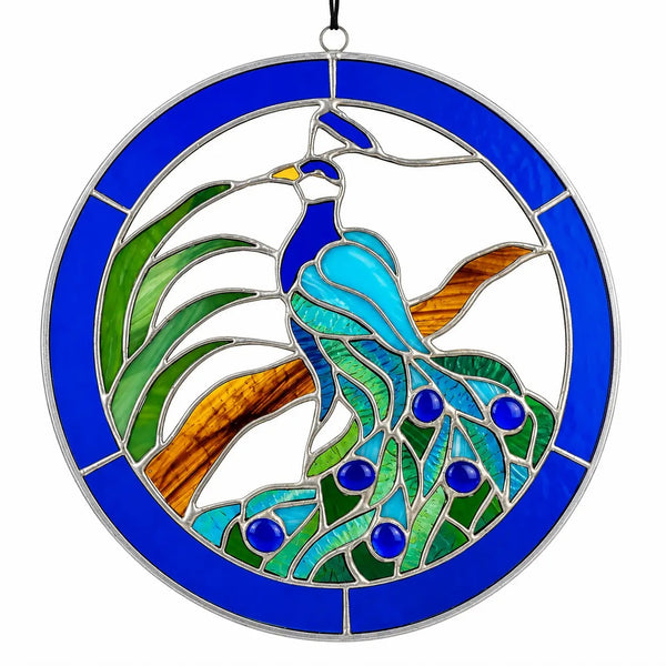 A circular stained glass hanging ornament featuring a peacock with blue, green, and turquoise glass panels, brown accents, and a bright blue border.