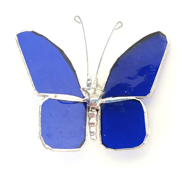 A butterfly-shaped suncatcher featuring four bright cobalt blue glass wings outlined in silver-tone metal, with thin silver antennae.