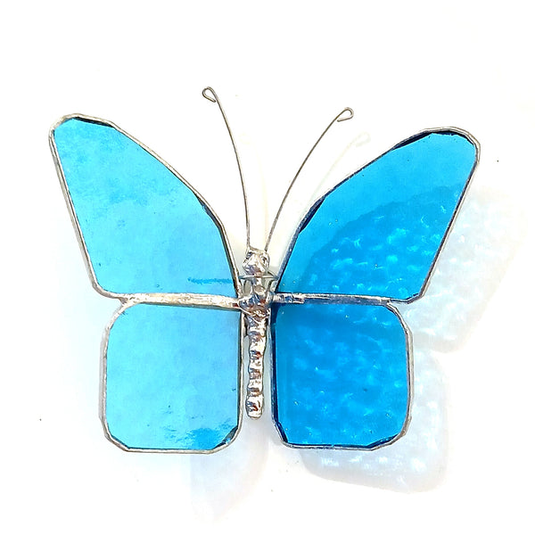 A butterfly-shaped stained glass window panel with bright blue glass sections and silver metal borders.
