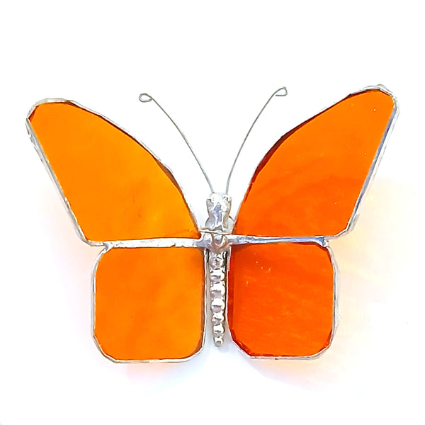 A butterfly-shaped hanging stained glass featuring vibrant orange glass panels outlined in silver metal, and thin wire antennae extending from the top.