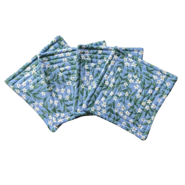 Quilted fabric coaster set with white flower pattern on a blue background.