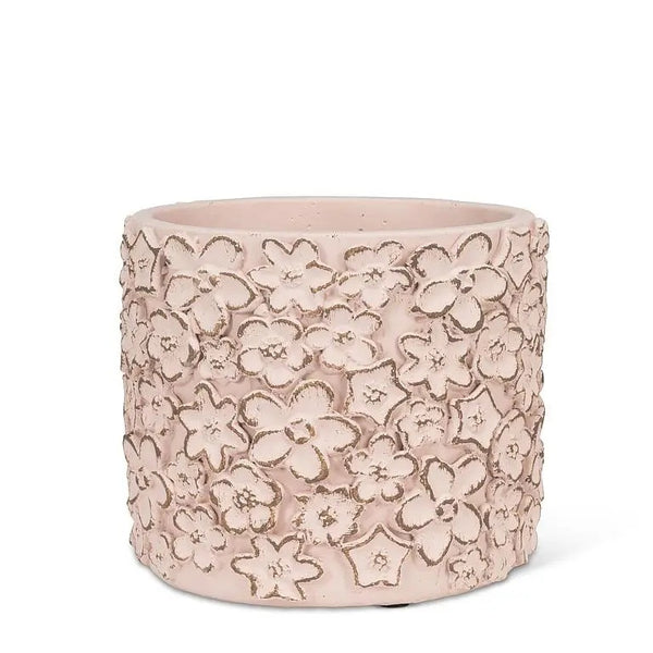 Round cement planter with pink sculpted flowers.