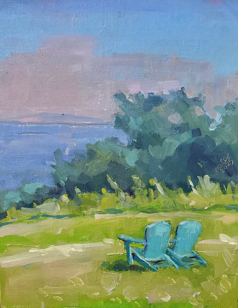 Two blue chairs on a grassy area with a scenic background of water and trees.