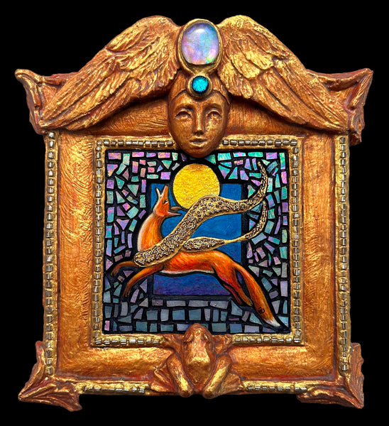 An ornate gold-toned decorative wall plaque featuring a sculpted face with wings, a deer leaping before a glowing full moon, and blue mosaic background.
