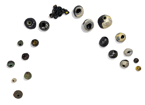 Arrangement of various black, white and gold round ceramic sculptures on a white background
