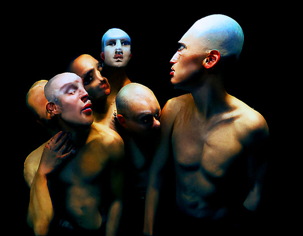 Artistic digital print of multiple bald figures with painted faces against a dark background