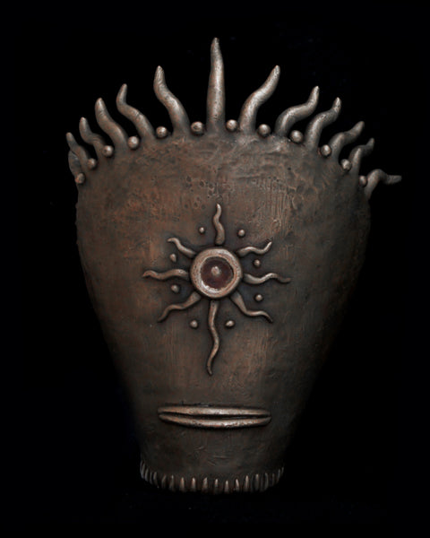 Bronze sculpture with sun design and tentacles protruding from the top.
