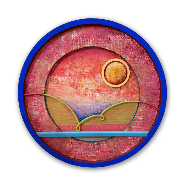 A circular abstract painted construction featuring a textured pink and red background with a blue outer border, a yellow sun, and green curved lines resembling a landscape or wave pattern, shown on a white background with a soft drop shadow.