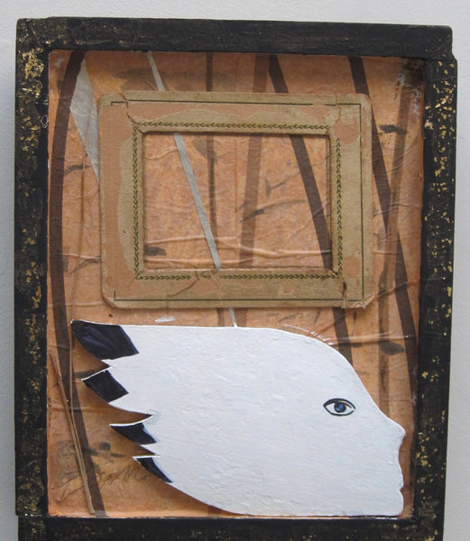 A square mixed-media art piece featuring a white paper head profile with black hair tips and a painted eye, layered over a brown paper background with vertical bark-like lines. A stitched tan rectangular frame sits near the top, all enclosed in a distressed black frame.