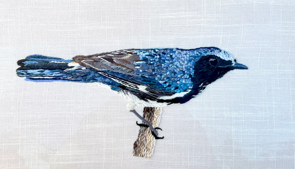 Blue and white embroidered bird illustration on a textured white background