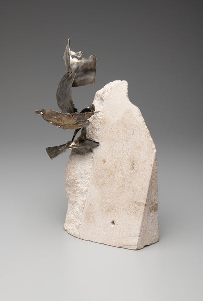 Abstract sculpture with metallic elements on a stone base against a gray background