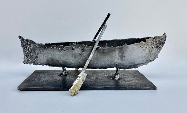 Abstract metal sculpture of a boat with two oars on a flat rectangular base.