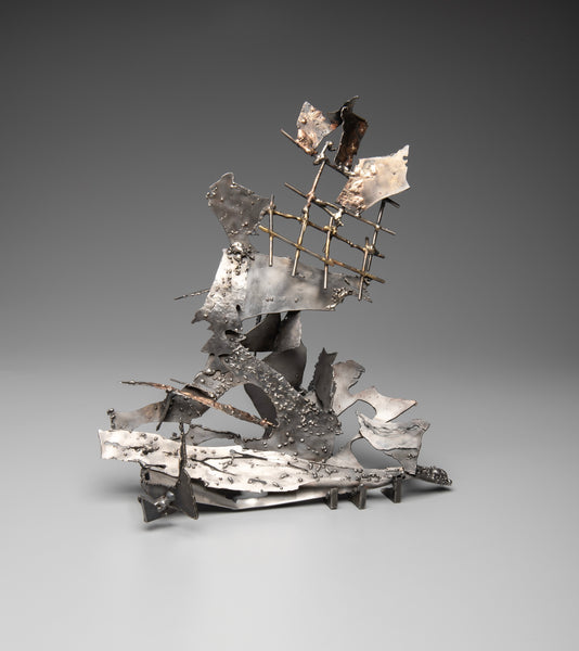 Abstract metallic ship sculpture on a gray background