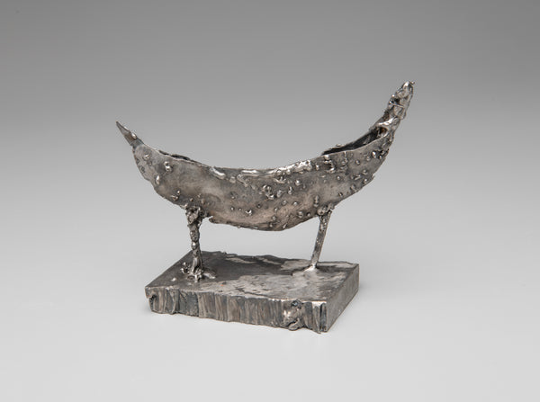 Metallic sculpture of a boat on a gray background