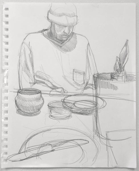 Pencil sketch of a person sitting at a table with bowls and a plant.