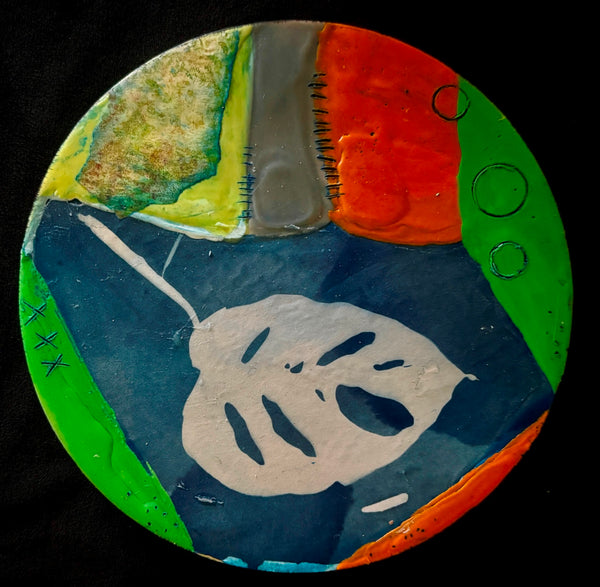 Circular abstract collage with a leaf and patches of bright colors