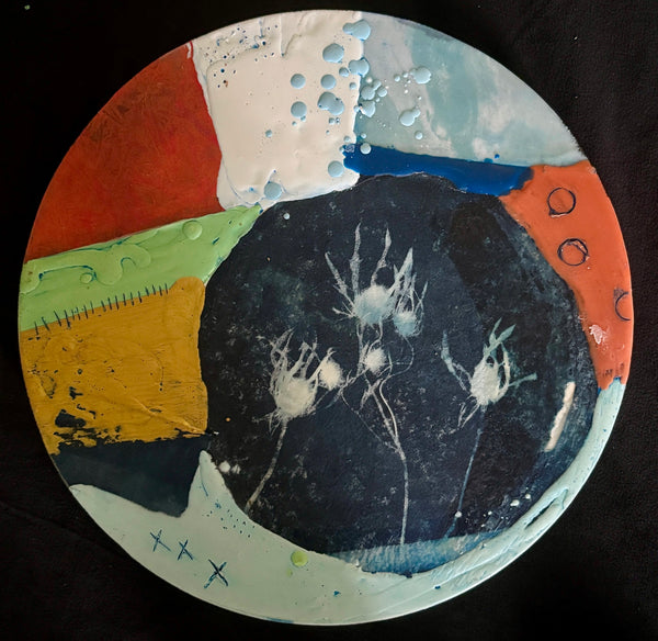 Circular abstract mixed media collage with a central black circle surrounded by colorful swatches of different textures