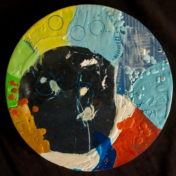 Circular mixed media collage with flowers against a dark background surrounded by patches of bright color and texture