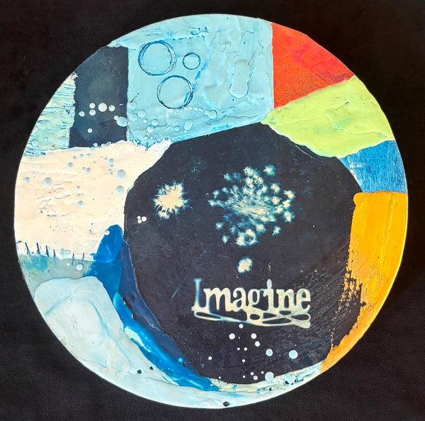 Colorful circular mixed media collage with the word 'Imagine' on a navy blue background surrounded by bright colors