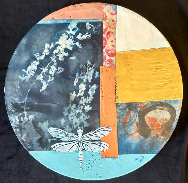 Circular painting with abstract design featuring a dragonfly, floral elements, and geometric shapes on a dark background.