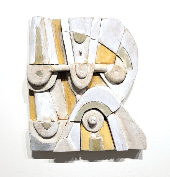 Abstract wood sculpture with geometric shapes in white, gold, and gray on a white background