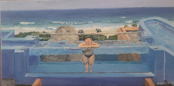 Person standing by an infinity pool with a scenic view of the ocean and beach.