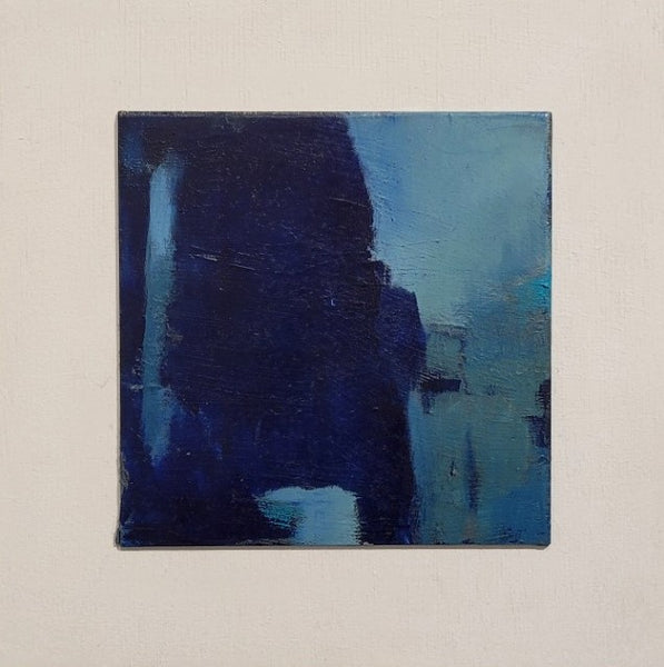 An abstract square canvas painting featuring textured brushstrokes of deep navy blue, light blue, and teal, mounted on a neutral off-white textured wall.
